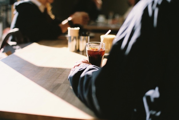 Cropped image of hand holding drink at cafe