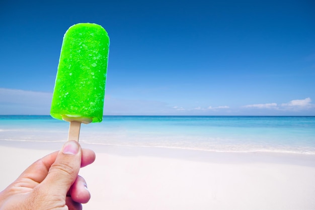 Cropped image of hand holding ice cream on beach