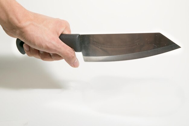 Photo cropped image of hand holding knife against white background