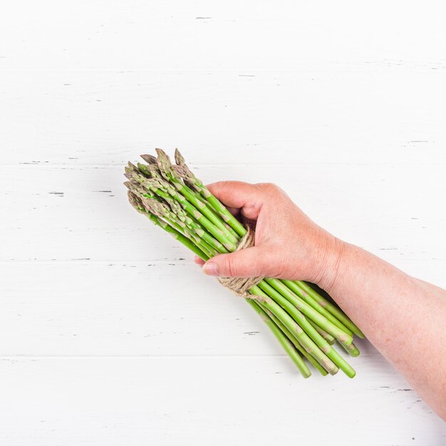 Foto immagine ritagliata di una mano che tiene una foglia su un tavolo sullo sfondo bianco