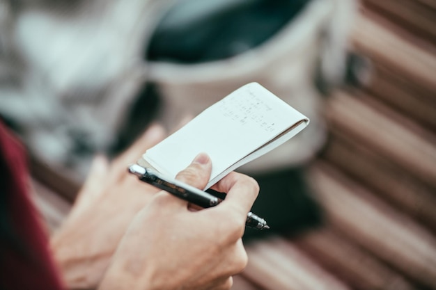 Photo cropped image of hand holding note pad with pen