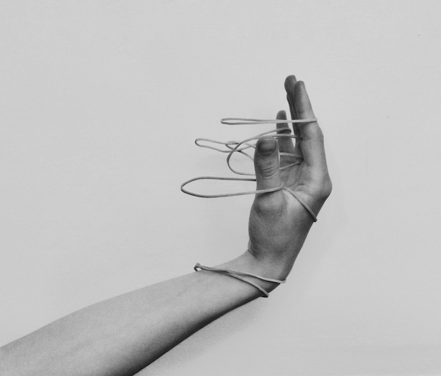 cropped image of hand holding rubber bands against wall