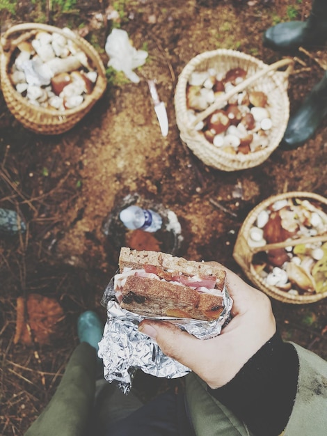 Photo cropped image of hand holding sandwich at outdoors