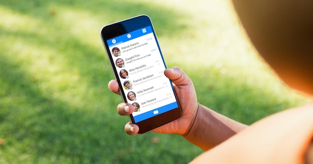 Foto immagine ritagliata della mano che tiene uno smartphone con l'elenco delle chat sullo schermo