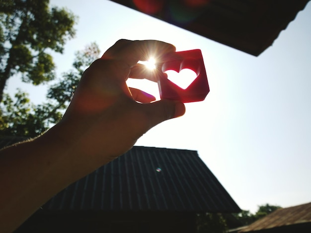 Cropped image of hand holding toy against sky