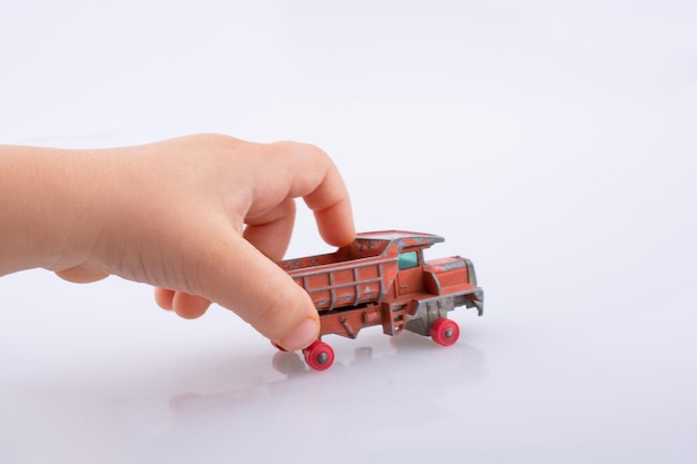 Photo cropped image of hand holding toy truck against white background