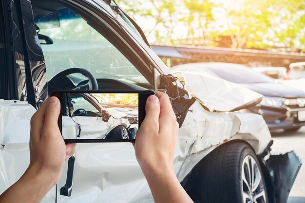 Photo cropped image of hand photographing damaged car through digital tablet