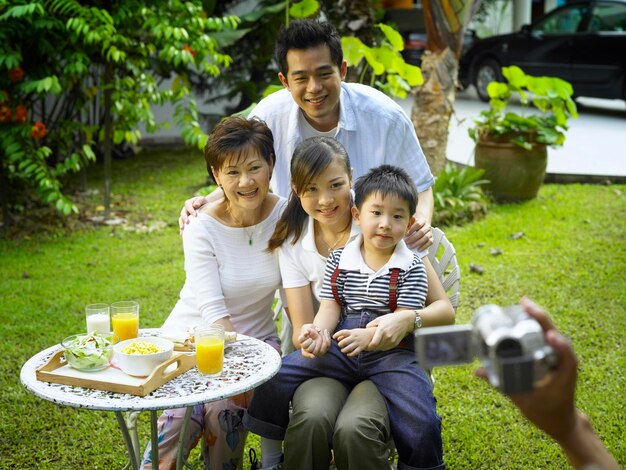 Photo cropped image of hand photographing family at back yard