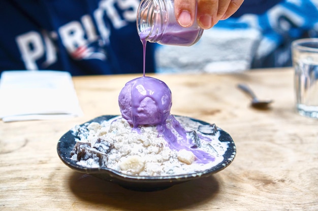 Foto immagine ritagliata di una mano che versa lo sciroppo sul dessert