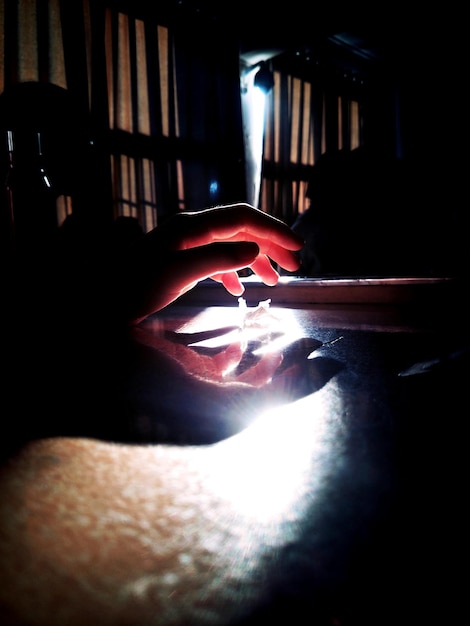 Foto immagine ritagliata di una mano che si estende verso la luce in camera oscura