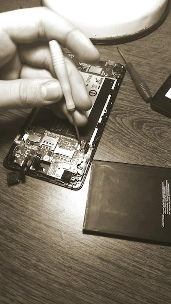 Foto immagine ritagliata di mano che ripara il cellulare al tavolo