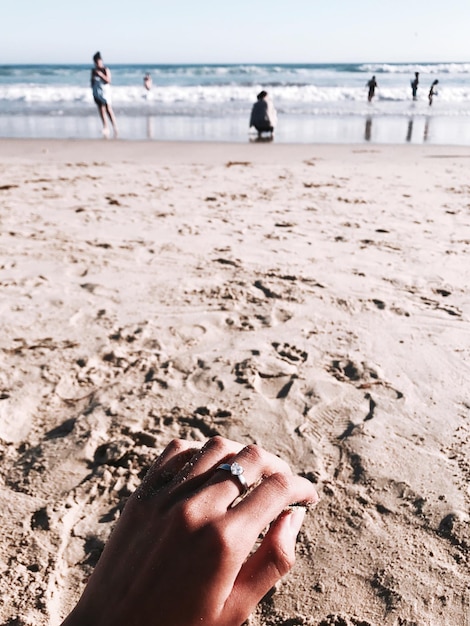 Cropped image of hand on sand at beach