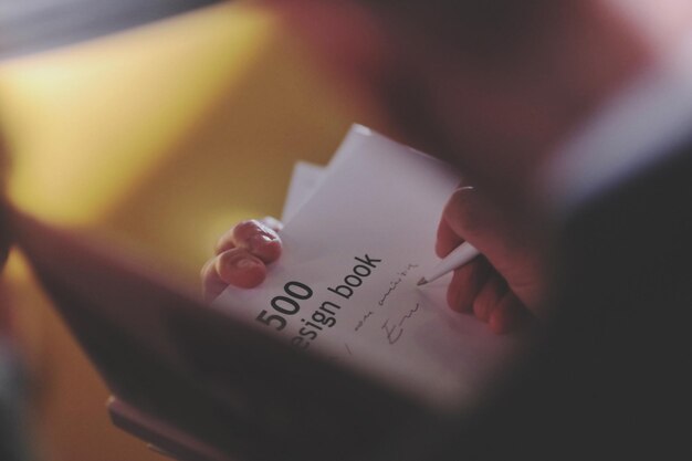 Cropped image of hand signing in book