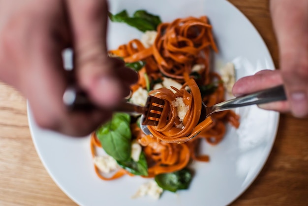 Foto immagine ritagliata di mani che mangiano pasta in un ristorante