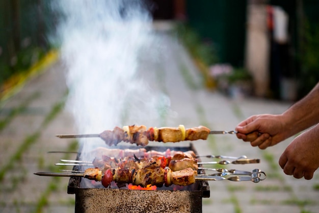Cropped image of hands preparing food on barbecue grill in back yard