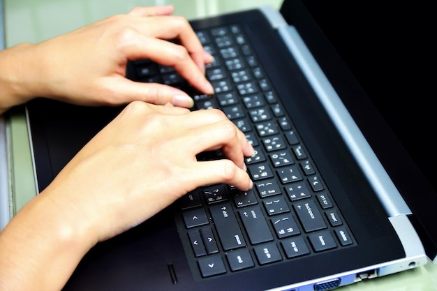 Photo cropped image of hands using laptop