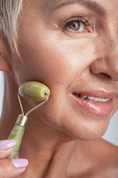 Cropped image of a healthy woman holding jade roller to her face