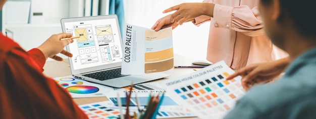 Foto immagine ritagliata del team di interior designer che discute il colore del materiale mentre il portatile visualizza il sito web i disegni di wireframe per dispositivi mobili app e sito web design creativo e concetto di business variegato