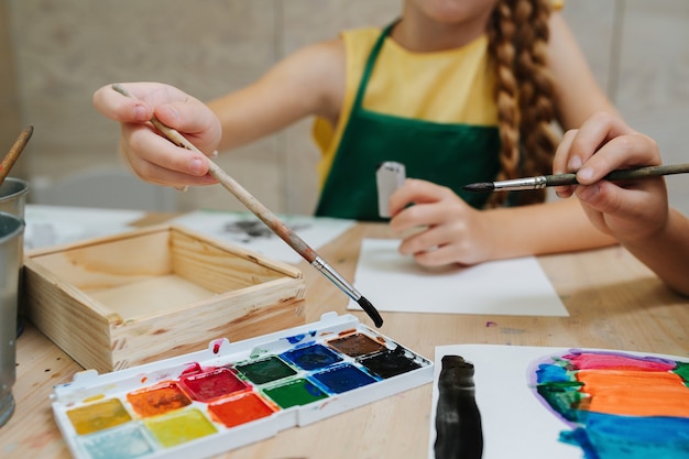 Cropped image of kids painting with watercolor low angle