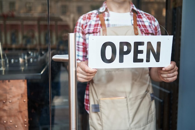 Photo cropped image of a male bartender standing with a sign open