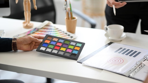 Cropped image A male graphic designer holding a colour swatch palette over creative office desk