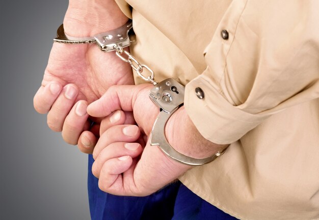 Photo cropped image of male hands in handcuffs behind his back