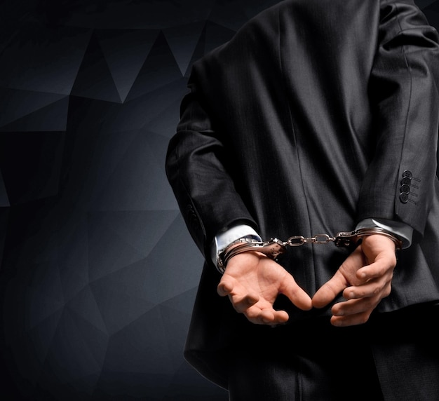 Cropped image of male hands in handcuffs behind his back