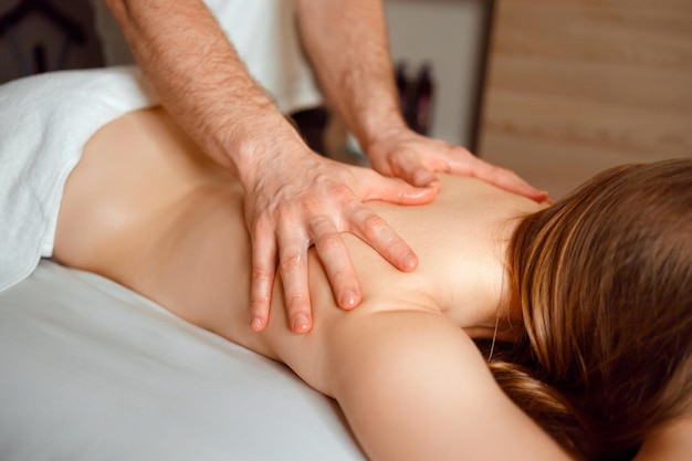 Cropped image of male masseur massaging woman at spa