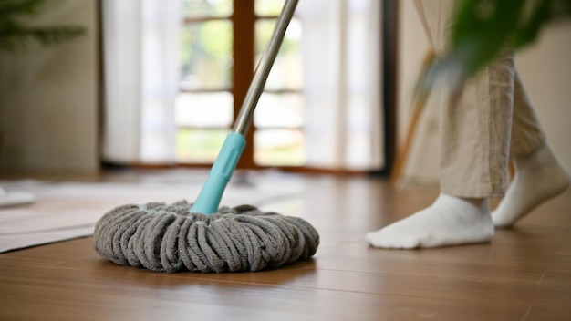 Cropped image of a man cleaning the floor with mop mopping the living room floor