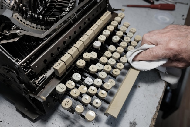 Foto immagine ritagliata di un uomo che pulisce una macchina da scrivere sul tavolo