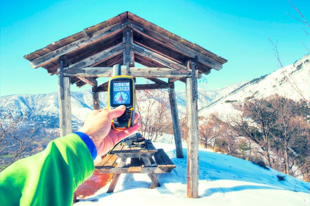 Photo cropped image of man holding global positioning system against gazebo