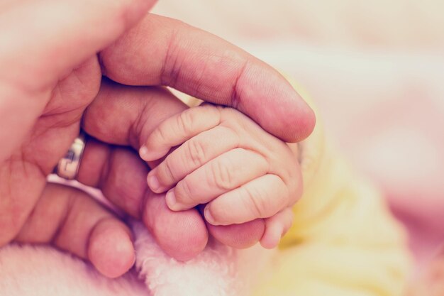 Photo cropped image of man holding hand of baby