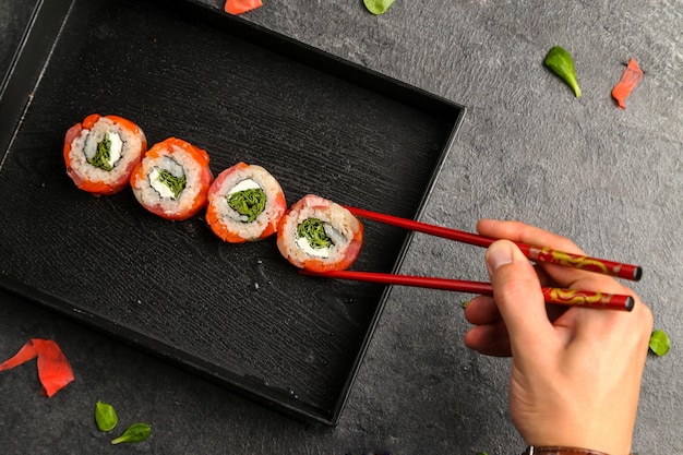 Foto immagine ritagliata di un uomo che tiene il sushi con le bacchette nel piatto