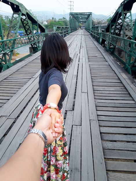 Photo cropped image of man holding woman hand on bridge