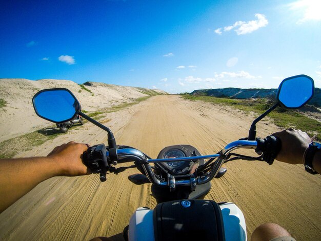 Cropped image of man riding motorcycle on dirt road