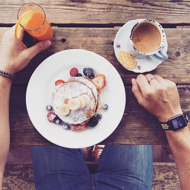 Photo cropped image of man sitting by breakfast at table