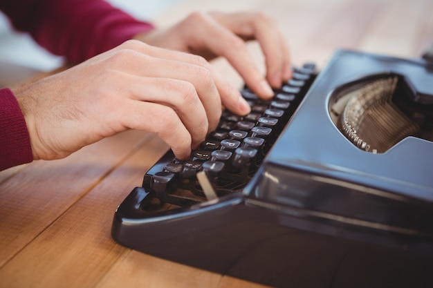 Cropped image of man typing on typewriter at desk