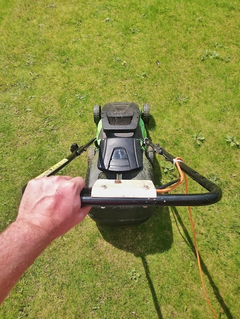 Photo cropped image of man using lawn mover on grassy field