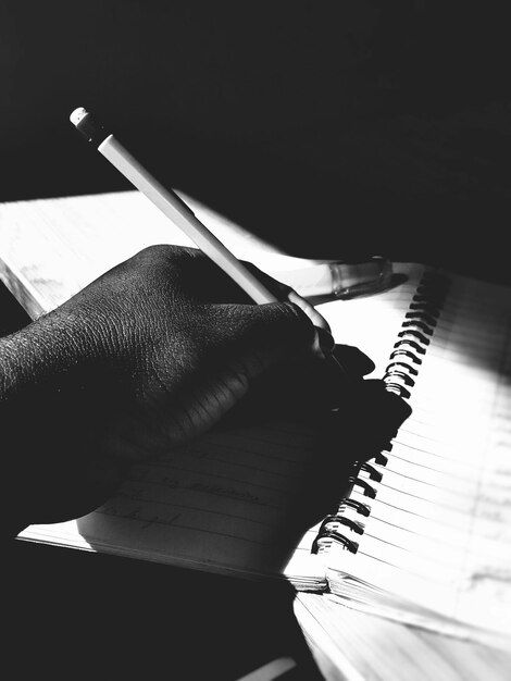 Photo cropped image of man writing on book