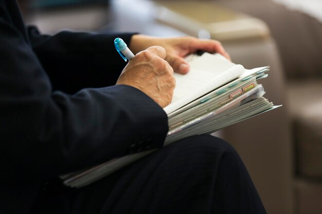 Foto immagine ritagliata di un uomo che scrive su carta mentre è seduto