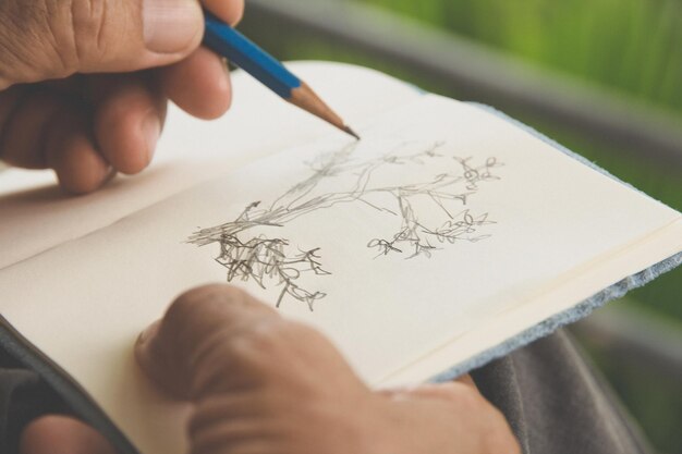 Photo cropped image of mature man drawing on book