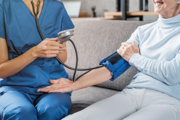 Cropped image of medical assistant measuring female patient blood pressure