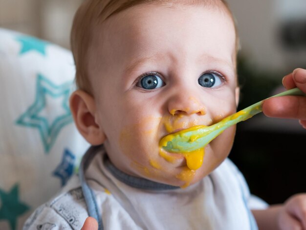 Photo cropped image of mother feeding baby at home