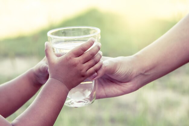 Photo cropped image of mother giving drinking water to kid