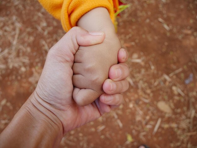 Photo cropped image of mother holding hands of kid