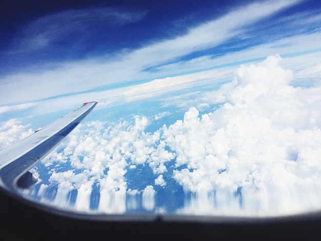 写真 雲の上にある飛行機の翼のクロップされた画像