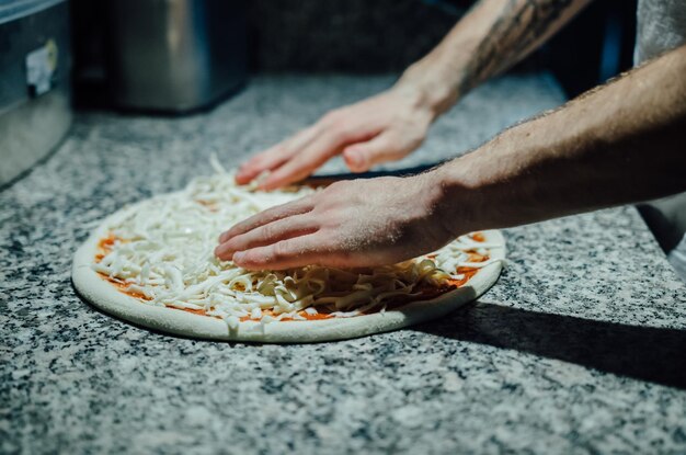 写真 キッチンカウンターでピザを準備しているシェフのカットされた画像