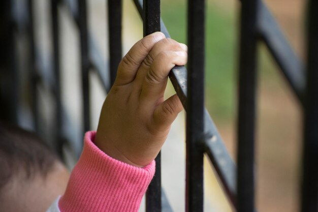 Фото Обрезанное изображение руки ребенка, держащей металлическую решетку