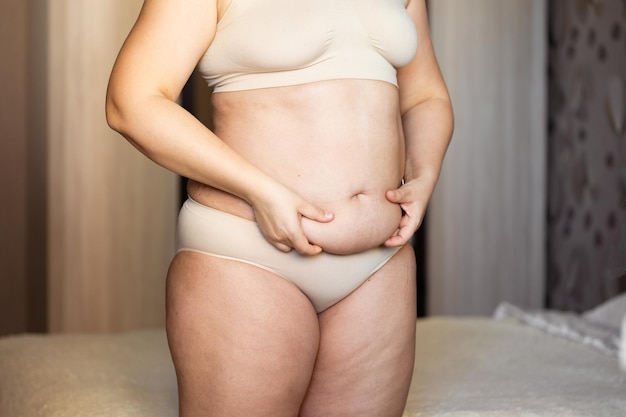 Cropped image of overweight fat woman holding sag stomach with obesity excess fat in underwear Abdomen flabs Close up