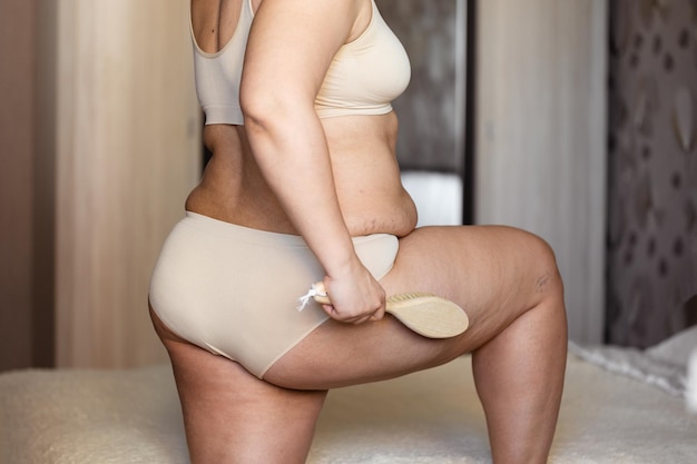 Photo cropped image of overweight woman in underwear doing brush dry massage rubbing puffy skin naked excessive waist